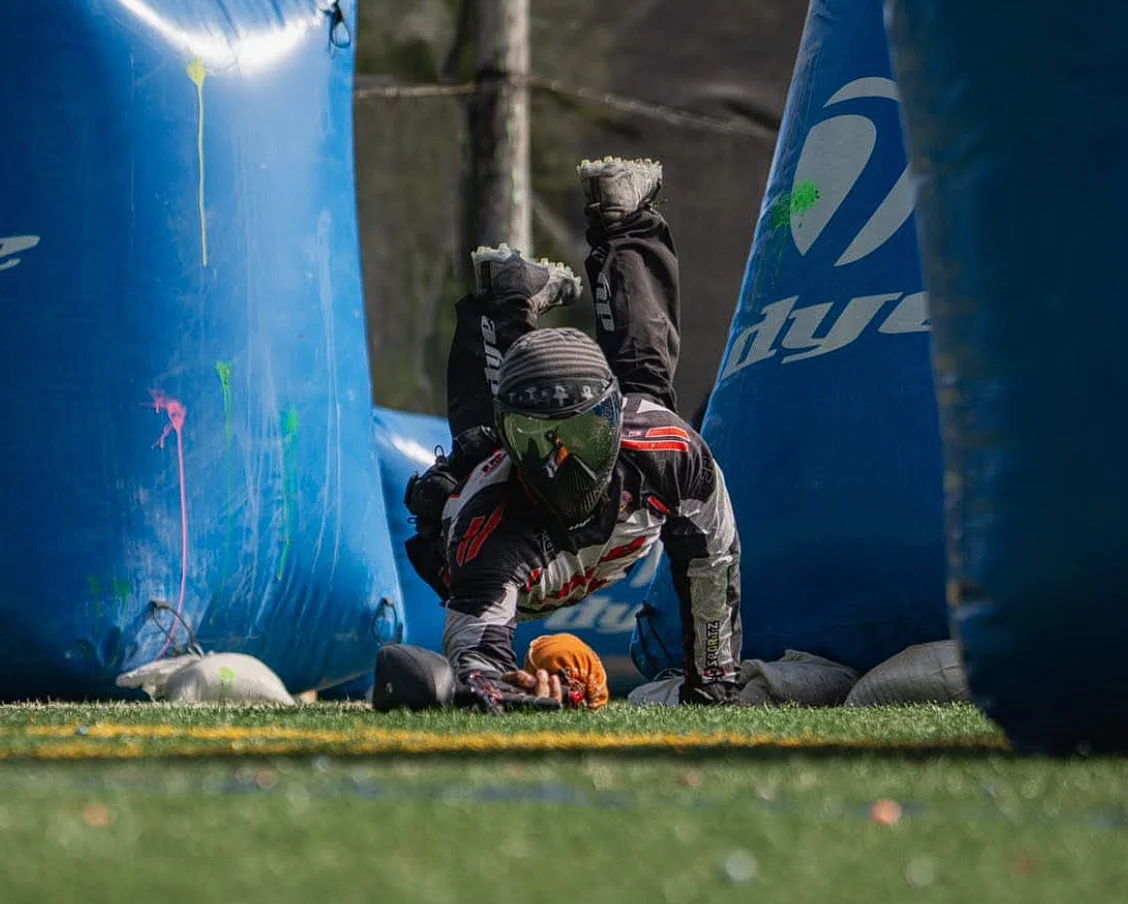 Paintball player dives between blue inflatable bunkers